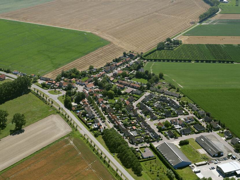 Een luchtfoto waarop een dorp en akkers worden getoond